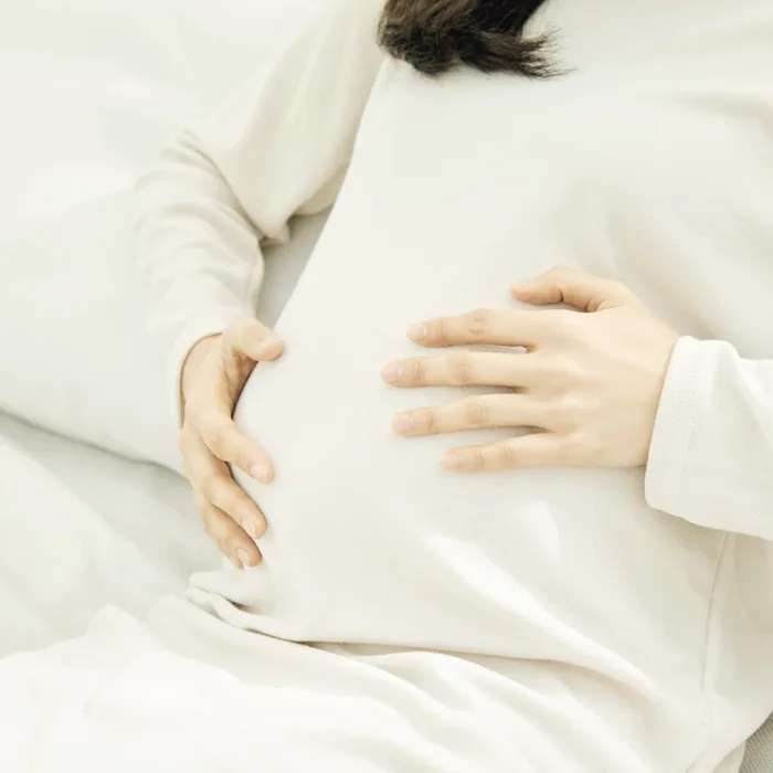 身着白衣、双手环抱腹部的孕妇